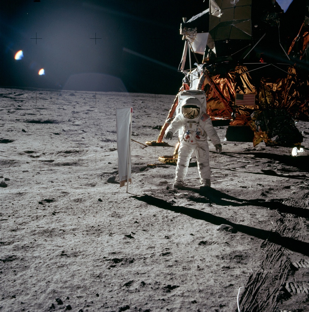 Buzz Aldrin astronauta estatubatuarrailargian Ilargi moduluaren ondoan, Apolo XI misioan (1969ko uztaila). Moduluaren azpian kakaz betetako poltsa zuri handi bat ikusten da.